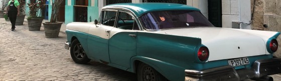 Foto achterkant groen met wit gekleurde oldtimer in een straat in Cuba.