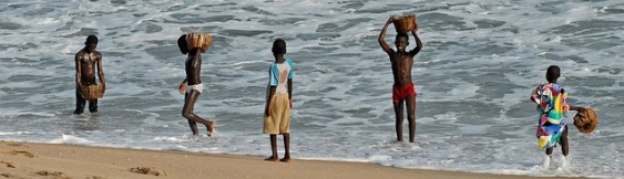 Vijf kinderen in de branding van strand in Ghana.