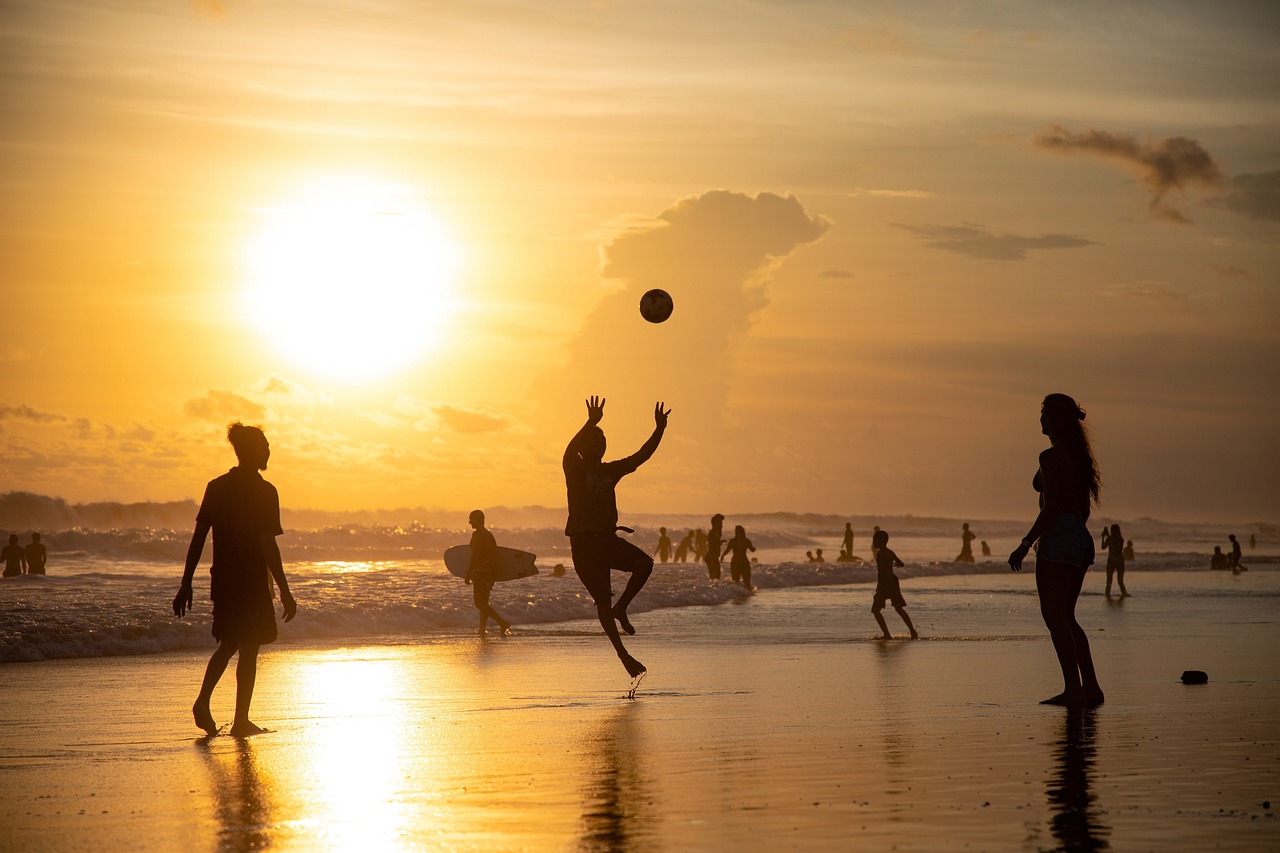 Foto jongeren op het strand met zonsondergang. Jongeren gooien bal over.